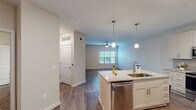 This single-story unit in Panama City Beach, Florida, offers a thoughtfully designed open-concept floor plan that maximizes functionality and flow. The living area features wood-look flooring, neutral walls, a ceiling fan, and a window that allows natural light to filter in, creating a bright and comfortable atmosphere.

The kitchen serves as the centerpiece of the main living space and is outfitted with white shaker-style cabinetry, granite countertops, and a gray subway tile backsplash. Stainless steel appliances include a French door refrigerator with ice maker, a range, a built-in microwave, and a dishwasher. A central island with an undermount sink and pendant lighting above provides additional prep space and casual seating potential.

The bedroom is generously sized, featuring plush carpeting, a ceiling fan, and a window with blinds. It connects directly to the full bathroom, which includes a soaking tub with subway tile surround, a granite-topped vanity, wood-look flooring, and a dedicated closet nearby.

Throughout the unit, consistent finishes—including neutral paint tones, clean trim work, and coordinated hardware—contribute to a cohesive and modern aesthetic well-suited for comfortable Florida living.