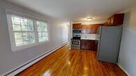 Located at 38 1/2 Wolden Road in Ossining, NY, this one-bedroom, one-bathroom residence offers a well-organized, single-floor layout designed for comfortable everyday living. Warm-toned hardwood floors run consistently throughout the main living areas, lending a cohesive and inviting character to the space.

The open living area is bright and airy, with large multi-pane windows that invite generous natural light and offer views of mature trees and the surrounding greenery. Baseboard heating is present throughout. The kitchen sits adjacent to the living area in an efficient open-plan arrangement, featuring rich cherry wood cabinetry, a tile backsplash, and a full suite of stainless steel appliances including a double oven range, microwave, and refrigerator.

The bedroom is a comfortable, well-proportioned room with its own window overlooking lush outdoor foliage, hardwood floors, and a double-door closet for storage. The bathroom is clean and neatly appointed, with a tiled tub-shower surround, a vanity with medicine cabinet, and tile flooring. Additional storage is available via a second closet. The hallway entry features built-in shelving and a glass-panel door leading to the private patio, which overlooks a parking area framed by mature trees.