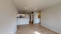 This single-story residence is thoughtfully designed with a neutral color palette and a blend of hard and soft flooring surfaces throughout. The open-concept living and kitchen area forms the heart of the home, where light wood-tone laminate flooring flows seamlessly underfoot. The kitchen is well-appointed with white cabinetry, granite-style countertops, and a full suite of stainless steel appliances, including a refrigerator, electric range, built-in microwave, and dishwasher. A peninsula counter separates the kitchen from the living area, providing additional prep space and a natural gathering point. Recessed lighting illuminates the kitchen and living space, while angled ceiling details add architectural character.

The bedrooms feature plush carpet and windows fitted with horizontal blinds that allow natural light to filter in. Ceiling fans are present in select bedrooms, adding to overall comfort. One bedroom connects directly to a full bathroom equipped with a soaking tub, while a separate full bathroom features a walk-in shower, white vanity cabinetry, and granite-style countertops. A dedicated laundry closet with washer and dryer hookups adds practical convenience to the layout.