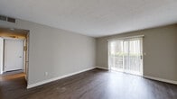 Located at 2210 Sullivan Rd in College Park, GA, this 2-bedroom, 2-bathroom residence offers a practical and comfortable single-floor layout. The living room is a welcoming space highlighted by rich, dark hardwood-style flooring and a large sliding glass door fitted with vertical blinds, allowing generous natural light and a view of the surrounding greenery. The kitchen is outfitted with white cabinetry, light countertops, a stainless steel refrigerator, and a dishwasher, providing a clean and functional cooking area. Both bedrooms feature soft carpeting and dedicated closet space — the primary bedroom includes a walk-in closet with built-in shelving, while the second bedroom offers a double bi-fold door closet with dual hanging rods. Neutral, warm-gray walls throughout the home create a cohesive and versatile backdrop. The two bathrooms are each finished with wood-style flooring, white vanities, and tub-shower combinations with white tile surrounds. A hallway connects the rooms, contributing to the efficient flow of the layout. Textured ceilings add a classic touch to the overall design of the home.