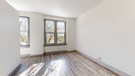 Located at 806 E Chestnut St in Louisville, KY, this three-bedroom, one-bathroom apartment offers a well-organized single-floor layout designed for comfortable everyday living. The entry area features light-toned hardwood-style flooring that extends through the common spaces, creating a clean and cohesive aesthetic throughout. Crisp white walls and generous natural light streaming through multiple windows with blinds give the unit a bright, airy feel.

The three bedrooms are thoughtfully sized, with the primary bedroom offering a comfortable footprint. Two of the bedrooms feature plush carpeting and multiple windows, including a corner window configuration in one room that fills the space with natural light and treetop views. The third bedroom also features hardwood-style flooring, a window with outdoor views, and convenient access to the hallway. Each room is enhanced by tall baseboards and paneled doors that add a classic architectural touch.

The bathroom is a standout feature, showcasing large-format marble-patterned wall tiles in white and grey with dark grout, paired with matte black fixtures and a soaking tub with shower. A dedicated closet and hallway round out the layout, providing practical storage. The unit's overall ambiance is clean, modern, and move-in ready.