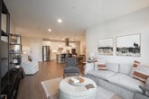Located at 303 Arrowhead Lane in South Setauket, NY, this thoughtfully designed single-floor, 3-bedroom, 2-bathroom home offers a seamless open-concept layout connecting the living, dining, and kitchen areas. The living room features light wood-style flooring, recessed lighting, and large windows that flood the space with natural light and offer views of the surrounding greenery. The gourmet kitchen is outfitted with crisp white shaker cabinetry, a subway tile backsplash, gleaming white countertops, stainless steel appliances including a French door refrigerator and double wall oven, and a central island with seating — ideal for both cooking and entertaining. A dedicated laundry room houses a full-size washer and dryer with built-in shelving for added storage. The bedrooms are generously proportioned, with plush carpeting and large windows overlooking the outdoors. One room functions well as a home office or flex space. Both bathrooms are finished with clean white vanities and marble-style tile surrounds — one with a walk-in glass shower. The home's neutral palette, quality finishes, and well-considered floor plan create a bright, comfortable, and functional living environment throughout.