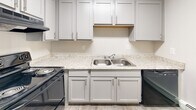 This single-floor unit at 4111 Glenwood Ave in Youngstown, Ohio, presents a cleanly updated interior with a neutral color palette and consistent wood-look luxury vinyl plank flooring throughout. The layout flows from a open living area into the adjoining rooms, offering a practical and cohesive design.

The kitchen features white shaker-style cabinetry with brushed nickel hardware, light granite-look countertops, a stainless steel double-basin sink, and black appliances including a range and dishwasher. Ample upper and lower cabinet storage makes the space highly functional.

The living area is generously proportioned, with a ceiling fan with light fixture and baseboard heating units along the walls. Natural light filters in through multiple windows fitted with horizontal blinds, lending the space a bright, airy feel. An additional room offers a quieter retreat, also finished with the same flooring and baseboard heating.

The bathroom is finished in a clean, all-white palette, featuring a tiled tub and shower surround, a white vanity with an integrated sink, and wood-look flooring that ties seamlessly to the rest of the unit. A wall-unit air conditioner is also present in the living space, providing climate flexibility throughout the year.