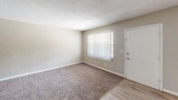 Located at 2050 South Ridgewood Avenue in South Daytona, Florida, this single-floor unit offers a practical and well-organized layout comprising two bedrooms, a living room, and a kitchen. The living area features a combination of light wood-style hard flooring and plush carpet, with neutral beige walls and a textured ceiling throughout. A ceiling fan with a light fixture provides comfort and illumination, while a large window fitted with vertical blinds allows ample natural light to fill the space. The entry door opens directly into this versatile common area. The kitchen is outfitted with white cabinetry, light countertops, a stainless refrigerator, and a dishwasher, all set on matching light wood-style flooring. Both bedrooms are carpeted and feature neutral walls, windows that bring in natural light with views of surrounding greenery, and textured ceilings. The primary bedroom is generously sized and includes a wide bi-fold louvered closet, offering practical storage. The second bedroom is similarly finished, providing a comfortable and functional space. Clean white baseboards and trim are consistent throughout, contributing to a cohesive and well-maintained interior aesthetic.