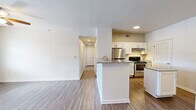 Located at 4730 N Nevada Ave in Colorado Springs, CO, this single-floor, three-bedroom, two-bathroom residence offers a well-designed layout with a clean, modern aesthetic throughout. The open-concept living and dining area flows seamlessly into the kitchen, which features white shaker-style cabinetry, granite countertops, stainless steel appliances including a range and refrigerator, and a peninsula with additional prep space. A louvered door off the kitchen leads to a dedicated laundry area. The living room is finished with wood-style flooring, a ceiling fan with light fixture, and a glass door that opens to a private balcony offering views of mature pine trees and the Colorado foothills beyond. The bedrooms are carpeted and well-lit, with the primary bedroom offering generous proportions and access to a walk-in closet equipped with wire shelving and a built-in shelving tower. The bathrooms mirror the kitchen's finishes, with granite vanity tops, white cabinetry, and wood-style flooring. Six total closets throughout the unit provide ample storage. The overall palette of warm neutrals, consistent finishes, and abundant natural light creates a bright, functional living environment well-suited for everyday comfort.