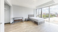 Located at 130 Columbia St W in Waterloo, Ontario, this modern 2-bedroom, 1-bathroom unit offers a well-designed, efficiently laid-out single-floor living space. The open-concept living room is bright and airy, featuring light wood-look flooring, a tray ceiling, recessed lighting, and floor-to-ceiling sliding glass doors that flood the space with natural light and offer elevated views of the surrounding cityscape. The kitchen is thoughtfully equipped with a mix of dark and light cabinetry, granite-style countertops, a white tile backsplash, and full-sized black stainless appliances including a range, dishwasher, and refrigerator. The primary bedroom is generously sized, with large windows framing urban views, light wood flooring, and ample room for furnishings. The second bedroom includes a built-in closet and continues the consistent modern aesthetic with the same light flooring and neutral wall tones. The bathroom features large-format tile flooring, a dark wood vanity with an integrated sink, a wall-mounted mirror with overhead lighting, and clean, minimalist finishes throughout. The unit's overall design is characterized by a cool, neutral palette of greys and whites, creating a contemporary and functional living environment.