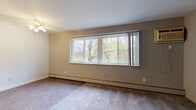 This 1-bedroom, 1-bathroom unit is thoughtfully laid out across a single floor, offering a practical and comfortable living environment. The spacious living room is a standout feature, showcasing a wide, multi-pane picture window that frames lush, tree-lined outdoor views and floods the room with natural light. Plush wall-to-wall carpeting and a ceiling fan add to the room's comfort and functionality. Baseboard heating is present throughout the carpeted areas, ensuring year-round warmth.

The galley-style kitchen is efficiently designed with white cabinetry lining both walls, providing ample storage space. It is equipped with a gas range, a full-size refrigerator, and a sink with a window-adjacent countertop, all set atop durable wood-look flooring.

The bedroom is generously sized, featuring soft carpeting, a ceiling fan with light fixture, a large window overlooking greenery, and a built-in closet with shelving for organized storage. Baseboard heating extends into this room as well.

The bathroom is clean and functional, featuring a full tub and shower combination with white tile surround, a pedestal-style sink, and wood-look flooring that ties the space together cohesively. The overall aesthetic is neutral and move-in ready throughout.