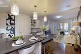 Located in Houston's desirable 77027 zip code, this well-appointed 2-bedroom, 2-bathroom residence offers a thoughtfully designed single-floor layout that balances style and functionality. The open-concept kitchen, dining, and living area serves as the heart of the home, featuring white shaker cabinetry, striking dark countertops, a spacious island with seating, and a trio of decorative pendant lights overhead. Rich hardwood flooring flows throughout the main living areas, complementing the neutral color palette. A built-in desk with shelving and cabinetry provides a dedicated workspace seamlessly integrated into the layout. The living room benefits from large windows dressed with floor-length curtains, allowing abundant natural light and offering views to the private patio beyond. The primary bedroom is a comfortable retreat with plush carpeting and direct access to its own closet. Both bathrooms are finished with marble-style tile; one features a glass-enclosed walk-in shower with a dark-countered vanity, while the second includes a full soaking tub. Additional highlights include a laundry area, pantry, ample closet storage throughout, and a welcoming entrance and hallway. The overall ambiance is modern and sophisticated.