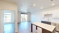 Located at 9990 E Harvard Ave in Denver, Colorado, this well-designed one-bedroom, one-bathroom unit offers a clean, contemporary aesthetic with thoughtful finishes throughout. The open-concept kitchen and living area serves as the heart of the unit, featuring light wood-style flooring, recessed lighting, and a ceiling fan that enhance both comfort and functionality. The kitchen is outfitted with stainless steel appliances — including a refrigerator, range, microwave, and dishwasher — paired with a two-tone cabinetry scheme of white upper cabinets and dark lower cabinets, a tile backsplash, and a central island with a white countertop that provides additional prep and dining space. A large sliding glass door in the living area opens to a private balcony, allowing natural light to fill the space and offering outdoor views. The bedroom is a well-proportioned, quiet retreat with the same light wood flooring and neutral white walls. The bathroom features a dark-cabineted vanity with a white countertop, an undermount sink with modern fixtures, a large round mirror, and a full shower-tub combination. Clean lines and a bright, neutral palette give the unit a modern, move-in-ready feel.