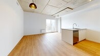 Located at 5630 Rue De Marseille in Montréal, this four-bedroom, two-bathroom unit offers a well-designed single-floor layout that balances industrial character with modern finishes. The open-concept living and kitchen area serves as the heart of the home, featuring striking exposed concrete ceilings, warm light hardwood flooring, and a sleek kitchen equipped with light wood cabinetry, a peninsula with an integrated sink, a stainless steel refrigerator, and a dishwasher. A pendant light fixture adds an industrial accent above the living space, which receives natural light through a sliding window. The hallway, distinguished by an exposed concrete column, connects the living areas to the four bedrooms, each finished with the same warm hardwood floors and exposed concrete ceilings. The primary bedroom includes a built-in closet and a window with exterior views. Two bathrooms serve the unit: one features a soaking tub, a wood-toned vanity, and large-format tile flooring, while the second offers a glass-enclosed layout with a wood vanity and mirrored cabinet. In-unit laundry is also present. The overall aesthetic is clean, contemporary, and cohesive throughout.