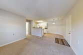Located at 13671 Cridercrest Pl in Woodbridge, VA, this one-bedroom, one-bathroom residence offers a thoughtfully organized single-floor layout designed for comfortable everyday living. The open-concept living and dining area is anchored by plush wall-to-wall carpeting and neutral gray walls, creating a bright, cohesive atmosphere. Natural light flows in through windows along the exterior wall, complemented by a door leading to a private patio—ideal for enjoying the outdoors. The kitchen is defined by a central peninsula with a dark countertop that serves as a natural divider between the cooking and living spaces. White cabinetry lines the walls, paired with matching white appliances including an electric range and refrigerator, and wood-look tile flooring ties the space together cleanly. A pendant light adds a finishing touch above the kitchen area. The bedroom is a well-proportioned retreat featuring carpeted flooring, large windows that invite natural light, and a mirrored sliding-door closet. The bathroom is finished with wood-look tile flooring, white cabinetry with a dark countertop, and a full tub-shower combination. A dedicated in-unit laundry area houses a full-size washer and dryer, adding everyday convenience. Multiple closets and a utility room provide ample storage throughout.