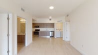 Located at 502 NW 207th St in Miami Gardens, FL, this single-floor unit features a clean, contemporary design throughout. Light-toned tile flooring flows consistently across the living areas, kitchen, hallways, and bedrooms, creating a cohesive and airy aesthetic. The open-concept layout connects the living area directly to the kitchen, which is outfitted with stainless steel appliances including a French door refrigerator, electric range, built-in microwave, and dishwasher. Warm wood-toned cabinetry extends from floor to ceiling, complemented by white countertops and a stainless steel sink. A dedicated laundry area with a washer and dryer is conveniently situated just off the kitchen. The bedrooms are bright and well-proportioned, with at least one featuring a window with exterior views of surrounding greenery. Walk-in closet space is accessible from the hallway. The bathrooms are finished with large-format tile, glass-enclosed walk-in showers, wood-toned vanities, white countertops, and framed mirrors. The spacious living area includes sliding glass doors that open to a railed balcony, allowing natural light to fill the interior and providing pleasant outdoor views.
