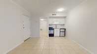 Located at 810 Village Ln in Winter Park, Florida, this single-floor unit offers a clean, functional layout finished throughout with light-toned ceramic tile flooring. Crown molding accents the main living area, adding a polished touch to the bright, neutral interior. A large sliding glass door fitted with vertical blinds allows generous natural light to fill the main living space, which also features a ceiling fan for year-round comfort.

The compact kitchenette is efficiently designed, featuring white cabinetry, a herringbone-patterned tile backsplash, granite countertops with an integrated sink, a gas range, and a stainless steel compact refrigerator—providing all essential cooking amenities within a streamlined footprint.

A dedicated walk-in closet offers built-in shelving and hanging rods, providing notable storage capacity. The bathroom includes a tub and shower combination, tile surround, a granite-topped vanity with white cabinetry, and brushed nickel fixtures, maintaining a cohesive, clean aesthetic throughout.

The overall ambiance of the unit is bright and minimalist, with a consistent white and neutral palette that creates an open, airy feel across all spaces.