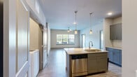 Located at 1005 Barnett Shoals Rd in Athens, GA, this single-floor, 2-bedroom, 2-bathroom residence offers a thoughtfully designed open-concept layout with modern finishes throughout. The kitchen serves as a central hub, featuring gray shaker-style cabinetry, granite countertops, a stainless steel appliance suite including a range, microwave, and dishwasher, and a kitchen island with a undermount sink and pendant lighting overhead. Wood-style plank flooring extends through the main living areas, complementing the neutral color palette and creating a cohesive aesthetic.

The living room benefits from multiple windows that invite natural light and views of the surrounding greenery, with a ceiling fan overhead. The primary bedroom is a well-sized retreat with plush carpeting, a ceiling fan, and a walk-in closet with wire shelving for organized storage. The second bedroom also features carpeted flooring, a ceiling fan, and natural light. Both bathrooms are finished with granite-topped gray vanities and tub-shower combinations. A dedicated in-unit laundry room houses a full-size washer and dryer with additional wire shelving above for storage convenience.
