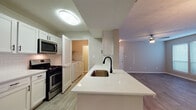 Located at 820 Canton Rd NE in Marietta, Georgia, this single-floor unit offers a thoughtfully updated interior with a clean, modern aesthetic throughout. The kitchen is a standout feature, boasting crisp white cabinetry with matte black hardware, white quartz countertops, a subway tile backsplash, and stainless steel appliances including a gas range, over-the-range microwave, and dishwasher. A peninsula with an undermount sink provides additional prep space and connects seamlessly to the adjoining living and dining areas. The open-concept living and dining space is finished with wood-look luxury vinyl flooring and features a ceiling fan with light, as well as window blinds that allow for natural light. A dedicated in-unit laundry room houses a full-size Whirlpool washer and dryer with overhead shelving. The bedrooms are carpeted and offer a comfortable, quiet retreat, each with natural light from windows. The bathroom is well-appointed with white shaker-style cabinetry, quartz countertops, brushed nickel hardware, and a large vanity mirror. Neutral gray tones carry throughout the unit, creating a cohesive and move-in-ready living environment.
