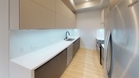 Located at 3833 Dunn Dr in the Culver City area of Los Angeles, this contemporary single-floor residence showcases a clean, modern aesthetic throughout. Light wood laminate flooring runs continuously across all living areas, creating a warm and cohesive feel. The open living area is bathed in natural light, with large sliding glass doors offering views of the surrounding urban landscape and access to a private balcony.

The galley-style kitchen is thoughtfully designed with sleek two-tone cabinetry in taupe and charcoal, a crisp white countertop, glass tile backsplash, a matte black faucet, and stainless steel appliances including a gas range and dishwasher. Recessed lighting throughout the unit provides bright, even illumination.

The bedroom features floor-to-ceiling black-framed sliding glass doors leading to an outdoor balcony, mirrored closet doors, and a built-in shelving closet, maximizing both storage and natural light. Corner windows in an additional room frame sweeping elevated views of the Los Angeles skyline and surrounding neighborhoods, highlighting the unit's desirable upper-floor positioning.

The bathroom is finished with marble-style tile surround, a combined tub and shower with a rainfall showerhead, sleek black-framed glass enclosure, and a warm wood vanity, tying together the space's modern and refined design language.
