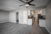 Located at 82165 Dr Carreon Blvd in Indio, California, this single-story unit offers a clean, modern interior with thoughtfully updated finishes throughout. Light-toned wood-look flooring extends seamlessly across the living areas and bedrooms, providing a cohesive and contemporary aesthetic, while textured ceilings and neutral warm-gray walls create a welcoming ambiance.

The living room is generously proportioned, featuring multiple windows fitted with blinds that allow abundant natural light to fill the space while maintaining privacy. A front entry door with an adjacent window further enhances the bright, open feel of the main living area.

The galley-style kitchen is efficiently designed with white shaker cabinetry, sleek chrome hardware, and granite-look countertops lining both sides. Stainless steel appliances — including a refrigerator, gas range, dishwasher, and sink — complete the well-equipped space, which also benefits from overhead lighting and dedicated ventilation.

The bedrooms are comfortably sized, each finished with the same wood-look flooring and neutral tones, with windows providing natural light. The bathroom is neatly appointed with a white vanity, undermount sink, granite-look countertop, a large mirror, and a shower/tub combination, reflecting the same updated style found throughout the unit. A hallway closet and interior doors with modern hardware add practical functionality to this well-maintained space.