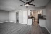 Located at 82165 Dr Carreon Blvd in Indio, California, this single-story unit offers a clean, modern interior with thoughtfully updated finishes throughout. Light-toned wood-look flooring extends seamlessly across the living areas and bedrooms, providing a cohesive and contemporary aesthetic, while textured ceilings and neutral warm-gray walls create a welcoming ambiance.

The living room is generously proportioned, featuring multiple windows fitted with blinds that allow abundant natural light to fill the space while maintaining privacy. A front entry door with an adjacent window further enhances the bright, open feel of the main living area.

The galley-style kitchen is efficiently designed with white shaker cabinetry, sleek chrome hardware, and granite-look countertops lining both sides. Stainless steel appliances — including a refrigerator, gas range, dishwasher, and sink — complete the well-equipped space, which also benefits from overhead lighting and dedicated ventilation.

The bedrooms are comfortably sized, each finished with the same wood-look flooring and neutral tones, with windows providing natural light. The bathroom is neatly appointed with a white vanity, undermount sink, granite-look countertop, a large mirror, and a shower/tub combination, reflecting the same updated style found throughout the unit. A hallway closet and interior doors with modern hardware add practical functionality to this well-maintained space.