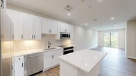 This thoughtfully designed one-bedroom, one-bathroom residence in Maplewood, NJ offers a bright, open-concept layout with clean modern finishes throughout. The combined kitchen and living area forms the heart of the home, anchored by a stunning quartz-topped island with striking veining. The kitchen is outfitted with crisp white shaker cabinets, a subway tile backsplash, stainless steel appliances including a refrigerator, dishwasher, built-in microwave, and range, plus a deep undermount sink with a matte black faucet. Recessed lighting illuminates the space, while warm wood-tone flooring flows continuously throughout, adding natural warmth to the neutral palette. The living area opens to a private balcony through sliding glass doors, offering peaceful treetop views of the surrounding greenery. The bedroom is a comfortable retreat with a large window framing leafy outdoor scenery, a dedicated walk-in closet, and easy access to the hallway. The full bathroom features large-format grey floor tile, a soaking tub with matte black fixtures, a warm wood vanity, and a frameless mirror. A hallway with additional closet space completes this well-appointed, move-in-ready home.