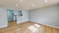 Located at 319 Columbia Ave in Stratford, New Jersey, this single-floor unit has been thoughtfully renovated with clean, modern finishes throughout. Light wood luxury vinyl plank flooring runs continuously across the main living areas, reflecting natural light and lending a warm, airy feel to the space. The living area is generously sized, featuring recessed lighting, soft neutral gray walls, and crisp white baseboards that give the interior a fresh, move-in-ready appearance. Large windows in the front room invite abundant natural light and offer views of the surrounding neighborhood, enhancing the open atmosphere. The kitchen is outfitted with white shaker-style cabinetry, white quartz countertops, a stainless steel sink, and stainless steel appliances including an electric range — presenting a clean and functional cooking space. A dedicated laundry area with a stacked washer and dryer unit adds everyday convenience. The bathroom is fully updated with large-format marble-look tile on the floors and surrounding the tub-shower combination, complemented by a white vanity and polished fixtures for a sleek, modern look. Throughout the unit, a cohesive color palette of soft grays and crisp whites creates a calm, inviting ambiance suitable for comfortable everyday living.