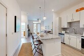 Located at 1835 Morehead Ridge Dr in Charlotte, NC, this thoughtfully designed one-bedroom, two-bathroom residence offers a bright and efficient single-floor layout. The open-concept living and kitchen area serves as the heart of the home, anchored by a large granite-topped kitchen island with bar seating, illuminated by stylish globe pendant lights. White shaker cabinetry, a subway tile backsplash, and stainless steel appliances complete the well-appointed kitchen. Light wood-style flooring flows throughout the main living areas, enhancing the airy, modern aesthetic. The living room is filled with natural light from French doors that open to a private balcony, and features a ceiling fan and clean white walls that lend a calm, contemporary feel. The spacious bedroom offers plush carpeting, natural light from large windows, and access to a generous walk-in closet with built-in wire shelving. The primary bathroom includes a granite vanity, a large mirror, light wood flooring, and a full soaking tub. A hallway connects the spaces efficiently, maintaining a smooth flow throughout. This residence combines modern finishes with a comfortable, livable design in a prime Charlotte location.