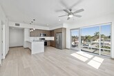 This well-appointed 2-bedroom, 2-bathroom residence offers a thoughtfully designed single-floor layout with a clean, modern aesthetic throughout. The open-concept kitchen and living area serves as the heart of the home, featuring light hardwood-style flooring, pendant lighting, and a large central island with a quartz countertop and undermount sink. The kitchen is equipped with stainless steel appliances — including a French door refrigerator, electric range, and built-in microwave — complemented by floor-to-ceiling wood-grain cabinetry and a classic tile backsplash. The living area connects seamlessly to the kitchen, benefiting from natural light and an open, airy feel. Both bedrooms are comfortably sized, featuring plush carpet flooring and ceiling fans. The primary bedroom includes a walk-in closet with built-in shelving, while the second bedroom features a soft blue accent wall, adding a touch of character. Each of the two full bathrooms is finished with large-format tile flooring, wood-tone vanity cabinetry, quartz countertops, and a soaking tub with a curved shower rod and mosaic tile accent band. Three hallways connect the spaces efficiently, and two closets provide ample storage throughout this well-organized residence.