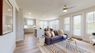 This single-story residence is designed around an open-concept floor plan that seamlessly connects the kitchen, dining, and living areas into one cohesive, light-filled space. The living room is anchored by large windows fitted with blinds that invite abundant natural light, complemented by a ceiling fan overhead and durable wood-look flooring underfoot. A dedicated dining area sits adjacent to the kitchen, illuminated by pendant lighting that adds a modern touch.

The kitchen is well-equipped with gray shaker-style cabinetry extending to the ceiling, white quartz countertops, a subway tile backsplash, stainless steel appliances, and a kitchen island with an integrated sink. Ample storage and counter space make it both functional and visually appealing.

The bedrooms are carpeted and generously sized, each featuring large windows that flood the rooms with natural light and ceiling fans for added comfort. The bathrooms are finished with the same gray cabinetry, white countertops, and wood-look tile flooring. One bathroom features a glass-enclosed walk-in shower, while another includes access to a walk-in closet with built-in shelving, offering practical storage solutions throughout.