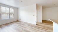 Located at 1101 National Ave in San Bruno, CA, this two-bedroom, one-bathroom unit offers a well-organized, single-floor layout designed for comfortable everyday living. Light wood flooring runs consistently throughout the space, creating a clean, cohesive aesthetic.

The kitchen is equipped with warm-toned wood cabinetry extending to the ceiling for generous storage, granite-style countertops, a built-in sink, and black appliances including a range, microwave, and refrigerator. A peninsula counter separates the kitchen from the open living area, which receives natural light through a window fitted with blinds.

Both bedrooms are bright and simply designed with white walls and the same light wood flooring. Each room features windows with exterior views and access to natural light. The primary bedroom offers a comfortable footprint, while the second bedroom is a cozy, functional space. A dedicated closet provides additional storage.

The bathroom includes a single-sink vanity with wood cabinetry, a dark granite-style countertop, a wide mirror with overhead lighting, and a full-size tub and shower combination. Grab bars are installed at the sink and tub areas, adding an accessibility-conscious detail to the space.