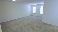 This single-floor space offers a clean, open layout defined by its neutral aesthetic and understated design. The main living area is generously sized, featuring wall-to-wall beige carpeting that adds warmth and comfort underfoot. Smooth white walls create a bright, airy atmosphere throughout, providing a versatile canvas ready for personalization. Two vertically oriented windows allow natural light to filter into the space, enhancing the sense of openness and keeping the interior feeling fresh and inviting. A ceiling fan is present overhead, contributing to both comfort and functionality. The overall ambiance is simple and uncluttered, with clean lines and a consistent neutral palette that makes the space feel calm and adaptable. The single-floor layout ensures easy accessibility and flow throughout. Whether used as a living area, bedroom, or flexible multipurpose room, the space offers a solid, move-in ready foundation with ample room to customize according to individual needs and preferences.