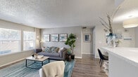 Located at 6244 Twin Oaks Dr in Colorado Springs, CO, this well-appointed one-bedroom, one-bathroom residence offers a thoughtfully designed single-floor layout. The open-concept living and dining area is anchored by a stone-surround fireplace and bathed in natural light from large windows with sliding patio door access. Wood-style flooring flows throughout, complementing the neutral gray tones and textured ceilings that define the space's clean, contemporary aesthetic.

The galley-style kitchen is outfitted with stainless steel appliances, white cabinetry with modern hardware, subway tile backsplash, and light stone countertops — a functional and attractive space for cooking and entertaining. The dining area sits just adjacent, offering a seamless transition between spaces.

The bedroom features a bold accent wall, a ceiling fan with light fixture, and natural light from a dedicated window. A walk-in closet provides generous storage, while the connected bathroom includes a full tub/shower combination with tile surround and wood-style flooring. A dedicated laundry area adds everyday convenience, rounding out a residence that balances comfort, style, and practicality in a compact, efficient footprint.