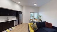 Located on Hollywood Boulevard in Los Angeles, this single-floor unit offers a thoughtfully designed open-concept layout finished with light wood-style flooring and crisp white walls throughout. The kitchen is a standout feature, equipped with dark cabinetry, white countertops, a white subway tile backsplash, and a full suite of stainless steel appliances including a refrigerator, range, microwave, and dishwasher. Generous upper and lower cabinet storage ensures ample functionality.

The kitchen flows seamlessly into the combined living and dining area, which benefits from notably tall ceilings that amplify the sense of openness. Large windows and a sliding glass door allow natural light to fill the space while offering views of surrounding greenery. Track lighting provides additional illumination for the dining area.

The bedroom is a comfortable, well-proportioned room featuring a sliding-door closet with a full-width hanging rod, ceiling fan, and the same warm flooring found throughout. The bathroom is clean and straightforward, featuring a shower-tub combination, toilet, and wood-style flooring, all finished in a bright, neutral palette that maintains the unit's modern, cohesive aesthetic.