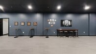 Located at 480 Myrtle St in New Britain, Connecticut, this single-floor entertainment space offers a thoughtfully designed environment ideal for social gatherings and recreational activities. The interior is defined by a bold two-tone color scheme — deep teal and slate blue walls paired with a dramatic black drop ceiling — creating a modern, immersive atmosphere throughout.

The open floor plan is divided into distinct activity zones. A game area anchors one end of the space, featuring a full-size pool table and an air hockey table, with sports-themed wall décor including framed photography and colorful graphic accents. Structural columns are integrated seamlessly into the design, painted to complement the surrounding palette.

A lounge zone offers comfortable seating, including a curved leather accent chair and additional soft furnishings arranged around a central coffee table, with a wall-mounted flat-screen television serving as a focal point. Framed sports artwork and motivational wall prints add character to the space.

Bar-height tables and stools are scattered throughout, providing casual seating options for groups. A dedicated wall display features board game artwork and a large-scale basketball canvas, reinforcing the sports and recreation theme. Light-toned tile flooring runs continuously throughout, contrasting the darker walls and ceiling. Recessed and pendant lighting ensure the space is well-illuminated across all zones.