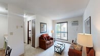Located at 2333 Long Ave in Saint Paul, Minnesota, this one-bedroom, one-bathroom unit offers a well-organized, single-floor layout that efficiently incorporates all essential living spaces. The living room is a comfortable, carpeted area bathed in natural light from large sliding windows and a glass door, providing views of the surrounding outdoor greenery. The neutral wall tones and textured ceiling contribute to a clean, understated aesthetic throughout.

The galley-style kitchen is thoughtfully designed with rich, dark espresso cabinetry lining both walls, light countertops, and wood-look flooring. It includes white appliances—a refrigerator and range—and offers ample cabinet and counter storage for efficient use of the space.

The bedroom receives good natural light through a sliding window overlooking outdoor foliage, creating a calm and restful atmosphere. It features carpeted flooring and a closet, providing functional storage. 

The bathroom is finished with tile flooring, a full tub-shower combination, a white vanity with storage, and clean neutral walls accented by framed artwork. A baseboard heating unit runs along the wall, consistent with the building's heating system. Overall, the unit presents a practical and comfortable layout suited for everyday living in Saint Paul.