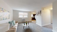 This single-floor residence offers a thoughtfully arranged layout that connects the living, dining, and kitchen areas in an open, cohesive flow. The living room is finished with plush grey carpeting and features a window unit air conditioner alongside baseboard heating, with natural light filtering in through blinds-covered windows. The space accommodates comfortable seating and a central coffee table, creating a relaxed, functional atmosphere.

The kitchen is well-equipped with dark espresso cabinetry, stainless steel appliances including a range, built-in microwave, and dishwasher, complemented by light granite countertops and a classic subway tile backsplash. Light-toned hardwood-style flooring extends through the kitchen and into the adjoining dining area, where there is ample space for a glass-top dining table and seating for four.

Both bedrooms feature soft grey carpeting, neutral walls, and windows that bring in natural light. Each room includes a closet with paneled doors, offering practical storage.

The bathroom maintains a clean, minimalist design with light tile flooring, a white vanity with brushed nickel hardware, and baseboard heating. Throughout the unit, the consistent neutral palette and modern finishes create a bright, inviting environment.