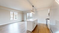 Located at 932 Maple Ave in Downers Grove, IL, this single-floor unit offers a contemporary, open-concept layout with modern finishes throughout. The kitchen serves as a central hub, featuring a large white island with ample storage, stainless steel appliances including a gas range, built-in microwave, and dishwasher, white cabinetry with matte black hardware, and a subway tile backsplash with white quartz countertops. A pendant light fixture with Edison-style bulbs hangs above the island, adding a stylish accent.

The kitchen opens directly into a spacious living area with light wood-tone flooring and a sliding glass door providing access to an outdoor balcony with urban views. Bedrooms are carpeted and well-lit by generously sized windows overlooking the surrounding Downers Grove streetscape. One bedroom includes a walk-in closet with built-in shelving and hanging rods.

Bathrooms are finished with clean, modern details. The primary bathroom offers a dual-sink white vanity with quartz countertops, a large mirror, and tile flooring. A secondary bathroom includes a tub-shower combination with white subway tile surround. A dedicated in-unit laundry area with a stacked washer and dryer adds everyday convenience. Neutral tones and wood-look flooring unify the space throughout.