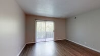 Located at 6516 N University St in Peoria, Illinois, this single-floor unit offers a well-organized layout with a clear distinction between living, sleeping, and functional spaces. The open living area features plush wall-to-wall carpeting, neutral gray walls, and a textured ceiling that adds subtle character. A full-width sliding glass door fitted with vertical blinds floods the room with natural light and provides access to outdoor views, creating an airy, welcoming atmosphere.

The galley-style kitchen is thoughtfully appointed with rich, warm-toned wood cabinetry, dark granite countertops, and wood-look vinyl plank flooring. Black appliances including a range and refrigerator lend a cohesive, practical aesthetic. The kitchen connects seamlessly to the main living area.

The unit includes multiple bedrooms, each finished with soft carpeting, neutral walls, and windows fitted with horizontal blinds that invite natural light while maintaining privacy. Closet space is provided in the bedrooms, including a walk-in closet option in one room, offering practical storage solutions.

The bathroom features a full-size soaking tub with a tub/shower surround in crisp white, complemented by wood-look flooring. Throughout the unit, a consistent neutral color palette and clean finishes create a calm, move-in-ready environment suited for comfortable everyday living.