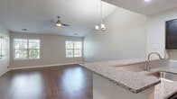 Located at 1731 Ontario Ave in Naperville, IL, this single-floor home offers four bedrooms and two full bathrooms within a well-designed, open-concept layout. The living room immediately impresses with its vaulted ceilings, an elegant chandelier, and a ceiling fan, all contributing to an airy and spacious ambiance. Rich, dark hardwood-style flooring extends throughout the main living areas, complemented by neutral gray walls that lend a clean, contemporary feel. Large windows allow ample natural light to fill the space, with views of surrounding greenery.

The kitchen is a functional highlight, featuring dark espresso cabinetry, granite countertops, stainless steel appliances, a track lighting system, and a peninsula that opens directly to the living area. Both bathrooms are finished with white tile surrounds, tub-shower combinations, and dark wood vanity cabinetry. The bedrooms offer a mix of hardwood-style and carpeted flooring, with several rooms showcasing vaulted ceilings and generous window coverage. The primary bedroom benefits from a sliding glass door that opens to an outdoor view. Overall, the home presents a cohesive, modern aesthetic throughout.