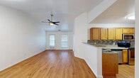 Located at 5501 Sayle St in Greenville, Texas, this single-story 2-bedroom, 2-bathroom home offers a thoughtfully designed open floor plan. The living room features warm hardwood-style flooring, vaulted ceilings, and a ceiling fan with light kit, creating a bright and airy atmosphere. Natural light flows in through multiple windows dressed with blinds, and a front entry door adds convenient direct access. The living area connects seamlessly to the kitchen via a breakfast bar peninsula, making the space ideal for both everyday living and entertaining. The kitchen is well-equipped with warm oak cabinetry, stainless steel appliances including a refrigerator, range, microwave, and dishwasher, complemented by a stylish tile mosaic backsplash and light countertops. Both bedrooms are carpeted and feature ceiling fans with light kits, offering a comfortable retreat. The spacious primary bedroom includes a walk-in closet with built-in shelving. The bathrooms are finished with oak vanities and granite-style countertops; one features a tub/shower combination, while the other includes a walk-in closet. Hardwood-style flooring flows throughout the main living areas, tying the home's cohesive, neutral aesthetic together.