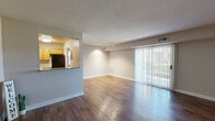 Located at 1808 Colonial Arms Cir in Virginia Beach, Virginia, this one-bedroom, one-bathroom residence offers a well-organized, single-floor layout designed for comfortable everyday living. The open-plan living and dining area is anchored by rich, dark hardwood-style flooring and a textured ceiling, creating a warm yet practical atmosphere. A large sliding glass door floods the space with natural light and provides outdoor views, while a track lighting fixture adds functional illumination overhead. The kitchen connects to the living area via a pass-through counter with granite-style surfaces, and is equipped with warm wood cabinetry, black appliances including a refrigerator, range, dishwasher, and microwave, as well as hardwood-style flooring that complements the main living space. The bedroom offers plush carpeting, a bright window with outdoor views, and access to two well-sized closets — including a walk-in closet outfitted with multi-tiered wire shelving for ample storage. The full bathroom features a tiled shower-tub combination with clean white finishes. Neutral tones throughout the residence create a cohesive, move-in-ready aesthetic, making this a practical and inviting home in Virginia Beach.