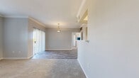 This thoughtfully designed single-floor residence offers a comfortable and functional layout encompassing one bedroom and one bathroom. The open-concept kitchen and living area serves as the heart of the home, with crown molding along the ceilings adding an elegant architectural detail. A pendant light fixture anchors the combined space, while a sliding glass door with vertical blinds allows abundant natural light and provides access to an outdoor balcony area. The flooring transitions between wood-look plank tile in the main living and kitchen areas and soft, neutral carpet in the bedroom zones.

The galley-style kitchen is efficiently arranged with gray cabinetry, white countertops, black appliances including a refrigerator and range, a stainless steel sink, and a louvered closet door leading to additional storage. The bathroom is clean and functional, featuring a full tub-shower combination with tiled surround, a vanity with a white countertop, gray cabinetry, and wood-look tile flooring.

The bedroom is generously sized, featuring a ceiling fan, a large window with outdoor views, and direct access to both a spacious walk-in closet outfitted with wire shelving and the full bathroom. The overall palette of soft grays, whites, and warm neutrals creates a calm, cohesive ambiance throughout.