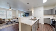 This single-story residence is thoughtfully designed with a cohesive neutral palette and hardwood-style flooring that extends throughout the entire unit, creating a unified and polished aesthetic. The kitchen serves as a central hub, featuring gray shaker-style cabinetry, light quartz countertops, a white subway tile backsplash, and a full suite of stainless steel appliances. A peninsula with an integrated sink and bar seating on the opposing side facilitates casual dining and open sightlines into the living area.

The living room is bright and inviting, benefiting from multiple windows that admit natural light and a ceiling fan overhead. Crown molding adds a refined architectural detail to this space. Adjacent to the living area, a dedicated dining nook features a contrasting gray accent wall and window access, creating an intimate setting for meals.

The bedrooms are well-proportioned, each equipped with ceiling fans and windows that provide natural light and outdoor views. A secondary bedroom offers flexible use as a guest room or office. The bathroom is finished with gray vanity cabinetry, a single sink, and a full tub-shower combination with crisp white surroundings, maintaining the clean and consistent design language found throughout the residence.