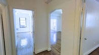 This single-floor space exudes a classic, timeless charm through its thoughtfully preserved architectural details. The interior is defined by elegant arched doorways that connect the rooms, creating a graceful flow throughout the layout. Rich hardwood floors run continuously underfoot, their polished surfaces reflecting natural light and adding warmth to the overall ambiance.

The rooms are generously bathed in natural light, courtesy of large windows that draw the eye and brighten the crisp white walls. The neutral, white-painted walls offer a clean and versatile backdrop, enhancing the sense of openness and airiness throughout the space. Decorative beam details add a subtle architectural interest to the ceiling, lending character without overwhelming the understated elegance of the interior.

The transition between rooms is smooth and intuitive, with the arched passageways serving as a distinctive design feature that sets this space apart. The combination of polished hardwood flooring, abundant natural light, and classic architectural elements creates an inviting atmosphere that feels both refined and livable. Overall, this space offers a harmonious blend of traditional character and bright, open living.