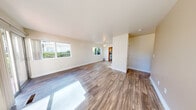 This well-appointed single-floor unit offers a clean, functional layout designed for comfortable everyday living. The spacious main living area is immediately welcoming, featuring warm wood-look plank flooring that extends throughout the common spaces, neutral-toned walls, and a ceiling fan overhead. Large windows along the perimeter flood the room with abundant natural light, offering views of surrounding greenery. The open layout provides a generous sense of space and versatility.

The kitchen is efficiently designed in a U-shaped configuration, outfitted with warm honey-toned wood cabinetry, rich dark granite countertops, and white appliances including a range, dishwasher, and refrigerator. A window above the sink brings in natural light, enhancing the workspace.

The bedrooms are carpeted for comfort and feature neutral walls and windows that look out to the exterior. Several bedrooms include built-in closets with shelving and hanging rods, providing ample storage. One bedroom benefits from a particularly generous closet with dedicated shelving units alongside a standard hanging section.

Additional spaces visible in the floor plan include a bathroom and a laundry area, rounding out the home's practical amenities. Throughout the unit, the consistent use of light, neutral tones and clean finishes creates a calm, cohesive ambiance.