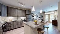 Located on Bay Area Blvd in La Porte, Texas, this one-bedroom, one-bathroom residence offers a thoughtfully designed single-floor layout. The open-concept kitchen and living area serves as the heart of the space, anchored by a granite-topped island with bar seating and elegant pendant lighting. The kitchen is outfitted with dark wood cabinetry, a classic subway tile backsplash, stainless steel appliances, and light hardwood-style flooring that extends throughout the main living areas. The living room is bright and inviting, featuring a ceiling fan, large French doors that welcome abundant natural light and provide outdoor access, and neutral-toned walls that create a warm, welcoming ambiance. The bedroom is a comfortable retreat with plush carpet flooring, a ceiling fan, and a generous window that frames lush outdoor views. The bathroom is finished with large-format tile flooring, a granite-topped wood vanity, and a full soaking tub with a tiled surround. A dedicated closet with built-in rods and shelving provides practical storage. Together, the modern finishes, natural light, and cohesive design make this a functional and attractive living space.
