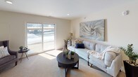 This single-floor, two-bedroom, two-bathroom residence is thoughtfully designed to maximize functionality and comfort. The open-concept kitchen serves as a central hub, featuring rich warm-toned cabinetry, granite-style countertops, stainless steel appliances including a refrigerator, range, microwave, and dishwasher, and a center island with bar seating—all set atop durable wood-look flooring. Recessed lighting throughout the kitchen and common areas enhances the bright, airy atmosphere.

The living area is generously proportioned, finished with plush carpeting, and anchored by a sliding glass door that invites natural light and outdoor views. A dedicated dining space sits adjacent, offering flexibility for everyday living.

Both bedrooms are carpeted and well-sized. The primary bedroom includes a spacious walk-in closet with built-in shelving and hanging rods, while the second bedroom features a standard closet and a bright window. Each bathroom is finished with wood-look flooring, warm wood vanities, white countertops, and open shelving for added storage. The overall palette of neutral tones and consistent finishes creates a cohesive, welcoming ambiance throughout the space.
