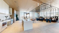 Located in the heart of Phoenix at 802 N 1st Ave, this sophisticated high-rise amenity floor spans an impressive 3,200 square feet of thoughtfully designed communal space. Floor-to-ceiling glass walls flood the interior with natural light while offering sweeping panoramic views of the Phoenix skyline, creating a seamless connection between the interior and the city beyond.

The open-plan layout encompasses a fully equipped chef's kitchen anchored by a striking marble island with seating, complemented by pendant lighting in a distinctive aqua tone. Adjacent to the kitchen, a formal dining area features a long communal table surrounded by bold teal upholstered chairs beneath a sculptural Sputnik chandelier, framed by a live plant wall and a slatted wood ceiling.

Multiple lounge zones are defined by richly patterned area rugs and curated furnishings, including a grand double-sided fireplace set in textured stone that serves as a dramatic architectural focal point. Warm wood-slat ceilings and dark steel partition screens add refined contrast throughout.

A welcoming entry hallway with textured blue-grey walls leads guests into the main space. Large-format stone tile flooring flows throughout, unifying each zone. Glass doors open directly to an outdoor terrace with a resort-style pool, lush landscaping, and ample lounge seating—ideal for year-round enjoyment in the Arizona sun.