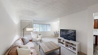 This 2-bedroom, 1-bathroom residence in Southfield, Michigan offers a well-organized single-floor layout designed for comfortable everyday living. The open living room serves as the heart of the home, featuring plush wall-to-wall carpeting, a tile-panel ceiling, and a large window dressed with vertical blinds that fills the space with natural light. A defined dining area sits just beyond, seamlessly connecting to the kitchen, which features wood-look flooring, dark cabinetry, and a dedicated dining nook. The primary bedroom is generously proportioned and includes a spacious walk-in closet outfitted with dual hanging rods and built-in shelving — providing excellent storage capacity. Additional bedrooms offer carpeted floors, vertical-blind windows for natural light, and closet access, making them well-suited for sleeping, guest accommodations, or a home office. A connecting hallway ties the rooms together efficiently. Throughout the residence, the neutral white walls and light finishes create a clean, bright ambiance. The consistent use of carpet in living and sleeping areas and hard-surface flooring in the kitchen and dining zone adds both comfort and practicality to the overall design of this Southfield home.
