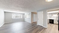 Located at 1714 Wellington Ave in Indianapolis, Indiana, this single-floor, 2-bedroom, 2-bathroom home features a thoughtfully updated interior with a clean, modern aesthetic. The spacious living room immediately impresses with wide-plank hardwood-style flooring, soft gray walls, a textured ceiling, and multiple windows dressed with horizontal blinds that fill the room with natural light. The layout connects seamlessly to the rest of the home via well-defined hallways. The kitchen is a standout, showcasing gray shaker-style cabinetry, crisp white quartz countertops, a stainless steel sink, black appliances including an electric range and refrigerator, and a skylight that adds brightness to the space. Both bathrooms are finished with matching gray vanities, white quartz countertops, and wood-look flooring for a cohesive, contemporary feel. The generously sized primary bedroom offers ample space and includes access to a dedicated walk-in closet with dual hanging rods and carpeted flooring. The second bedroom features plush carpet, a large window with natural views, and a textured ceiling. Throughout the home, consistent finishes and neutral tones create a clean, move-in-ready atmosphere.