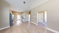 Located in Spring, TX, this well-appointed single-story home offers a clean, modern aesthetic across a comfortable footprint. Light wood-look flooring runs throughout every room, complemented by warm neutral wall tones and crisp white trim, creating a cohesive and inviting atmosphere.

The entrance opens into a hallway with notably high ceilings that carry through into the open-concept kitchen and living area, amplifying the sense of space. The kitchen is well-equipped with white flat-front cabinetry, dark countertops, a white subway tile backsplash, and stainless steel appliances including a refrigerator, dishwasher, microwave, and range. A window above the sink allows natural light to brighten the workspace.

The generously sized primary bedroom is a standout feature, offering ample square footage, two windows with window treatments, a ceiling fan, and a double-door closet — providing both comfort and storage. An additional smaller room with a window offers flexible use as an office or secondary space.

The bathroom is clean and functional, featuring a tub-shower combination with white tile surround, brushed nickel fixtures, and dark countertops. Throughout the home, panel-style doors with black hardware add a modern touch, while recessed lighting and ceiling vents ensure year-round comfort.