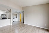This efficiently designed studio in Dallas, TX (75287) makes smart use of its single-floor layout, seamlessly combining the living, dining, and kitchen areas into one open, cohesive space. Light-toned luxury vinyl plank flooring flows throughout, complementing the neutral beige walls and white trim to create a clean, modern aesthetic. The living area is bright and airy, highlighted by vaulted ceilings that add a sense of height and openness, and a full-width sliding glass door fitted with vertical blinds that invites abundant natural light and opens to a private balcony with outdoor views. A ceiling fan adds comfort to the main living zone. The kitchen is well-appointed with stainless steel appliances — including a refrigerator, electric range, built-in microwave, and dishwasher — paired with white cabinetry, light quartz-style countertops, and a classic white subway tile backsplash. The bathroom features a full tub-and-shower combo with white tile surround, a toilet, and a vanity with wood-look flooring. A dedicated laundry area accommodates a washer and dryer, and a separate closet provides convenient storage. The textured ceilings throughout add a subtle traditional touch to this otherwise contemporary residence.